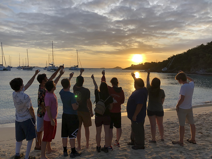 留学班的学生们对着太阳举起蓝色的弹珠.