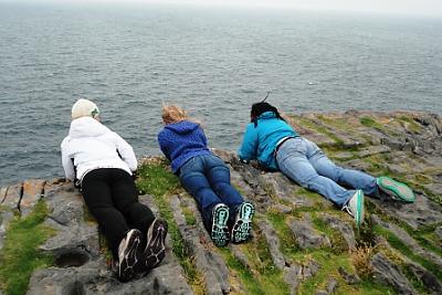 3 L和mark College students looking over the cliffs of Moher.
